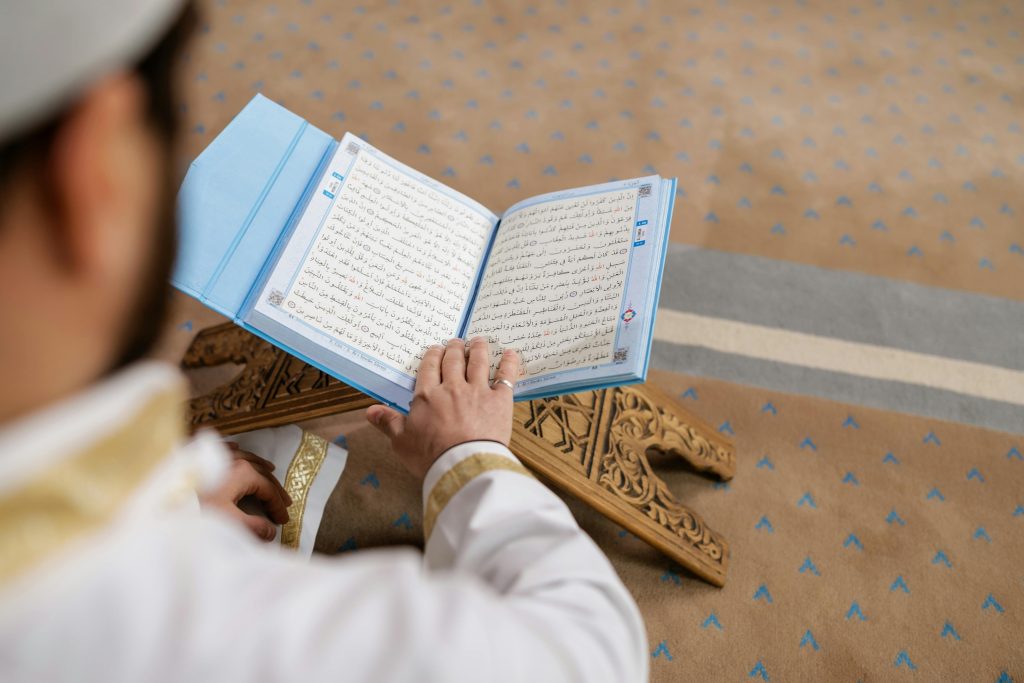 A man reading the Quran in a mosque, focusing on spiritual connection and religious devotion.